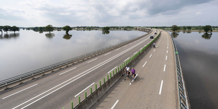 Fietsers op een fietspad bij een dijk.